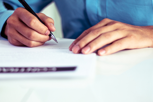 Man signing a document to illustrate CMS updates to Section 111 Model Language Form